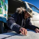 Man meet met een vochtmeter een oppervlak naast een caravan