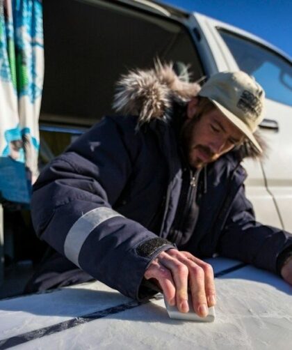 Man meet met een vochtmeter een oppervlak naast een caravan