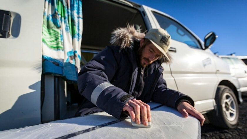 Man meet met een vochtmeter een oppervlak naast een caravan