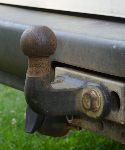 Close-up van een roestige trekhaak onder de achterbumper van een auto