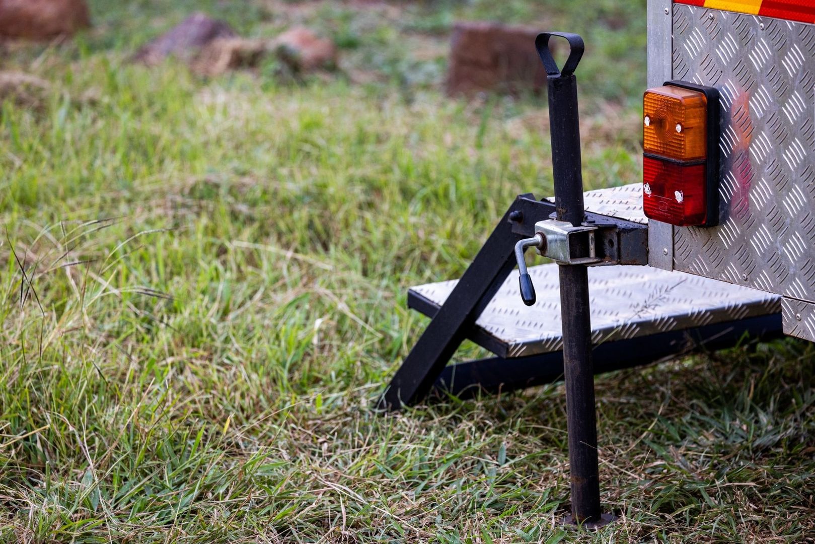 Aanhangerkoppeling met steunpoot en achterlichten op gras